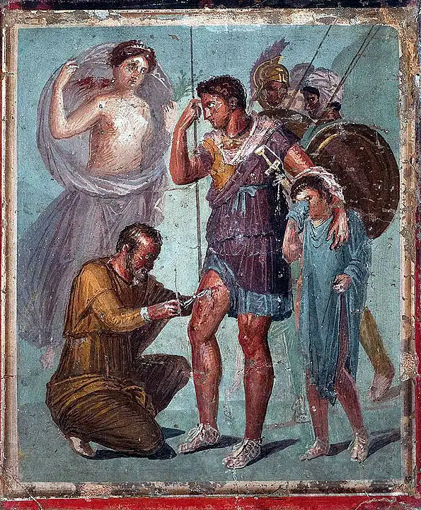Aeneas ist verwundet, ein Pfeil wird ihm aus dem Bein entfernt. Schützend bei ihm wie immer seine Mutter Aphrodite.